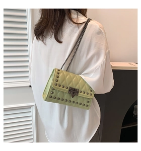 Model wearing a light green quilted leather crossbody bag with silver rivets and chain straps