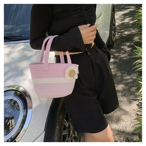Dettaglio della borsa tote intrecciata rosa e bianca con ciondolo a fiore e cotone