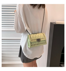 Detail of mint green quilted crossbody bag featuring silver studs and metal chain strap