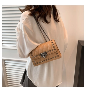 Detail of light khaki quilted crossbody bag with metal rivets and a chic chain strap