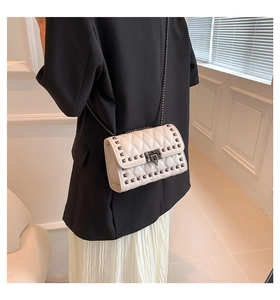 Detail of beige quilted leather bag featuring metal studs and geometric turn-lock