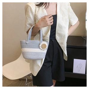 Detail of hand-woven striped tote bag featuring a 3D white daisy flower ornament