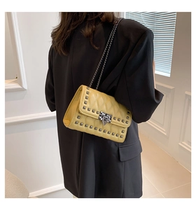 Detailed side view of yellow quilted crossbody bag with silver studs and chain strap