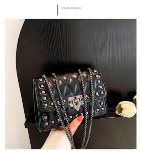 Detail of black quilted crossbody bag featuring silver square studs and metal chain strap