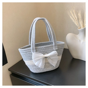 Dettaglio della borsa a mano intrecciata con un grande fiocco in organza bianca