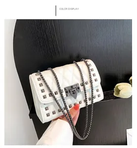Detailed view of white quilted crossbody bag with metal studs and chain strap