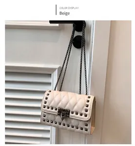 Close-up of beige quilted crossbody bag with metal chain strap and square studs