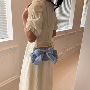 Blue tweed chain crossbody bag with a large chiffon bow shown on model's shoulder