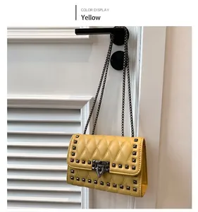 Detail of yellow quilted crossbody bag with metal rivets and bronze chain strap