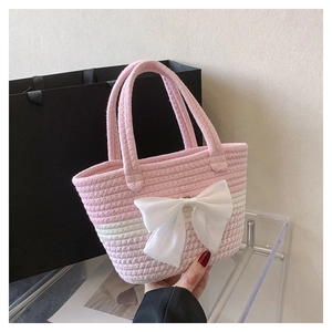 Detail of pink and white woven bag featuring a large decorative bow and top handles