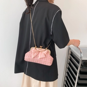 Pink tweed shell bag with silk bow and gold chain strap shown on a model side view