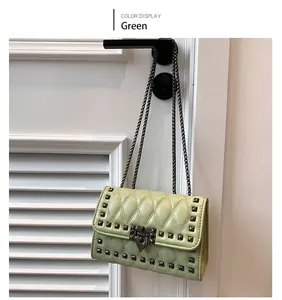 Close-up of green quilted shoulder bag featuring dark metallic studs and chain strap