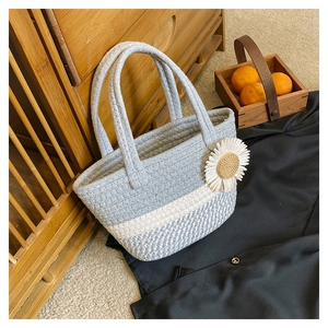 Close-up of woven hand-woven bag featuring light blue patterns and a white daisy floral accent