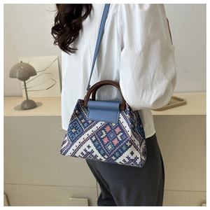 Detailed view of geometric jacquard patterns and elegant wooden handle on a crossbody bag