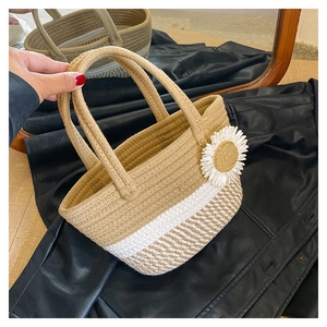Detailed close-up of woven cotton rope handbag with white daisy and plaid pattern texture