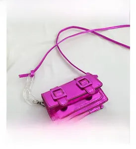 Detail of a bright pink mirror-finish mini crossbody bag with a transparent acrylic chain