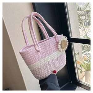 Detail of pink and white woven tote bag with a daisy charm against a natural window view