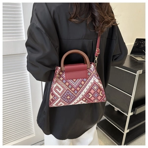 Detailweergave van een etnische geweven crossbodytas met houten handvat gedragen door model