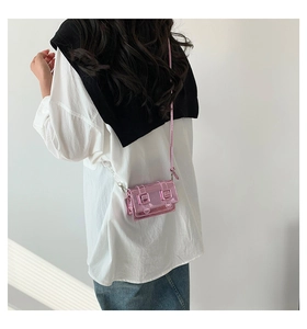 Detail of metallic pink square crossbody bag with mirror finish shown on a model
