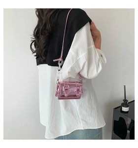 Detail of metallic pink mini crossbody bag with acrylic chain and silver buckles