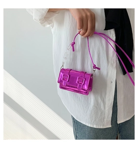 Detailed shot of a metallic pink mini square bag with buckle flip cover and acrylic chain strap