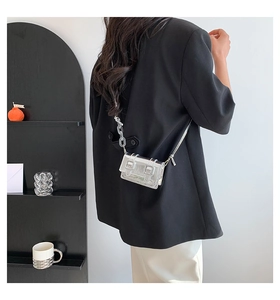 Detail of silver mirror mini crossbody bag with transparent acrylic chain on black blazer