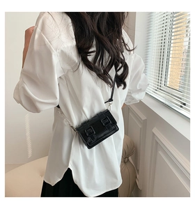 Detailed view of mini black glossy crossbody bag with retro belt buckle and silver hardware