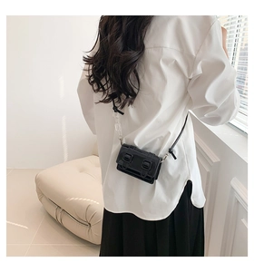 Detail of a black patent leather mini flap bag with trendy acrylic chain strap