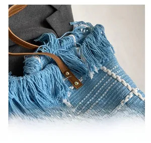 Vue détaillée du sac en tricot à carreaux bleu et blanc avec poignée en cuir et rivets