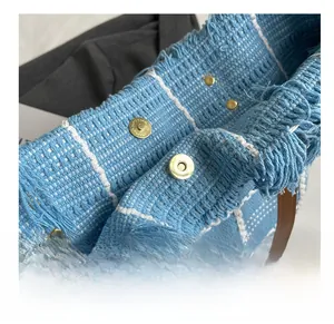 Détail des fermoirs magnétiques d'un sac cabas tissé à carreaux bleus et franges