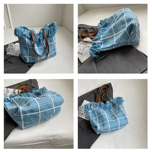 Detail view of blue woven tote bag with white grid pattern and stylish fringe edges