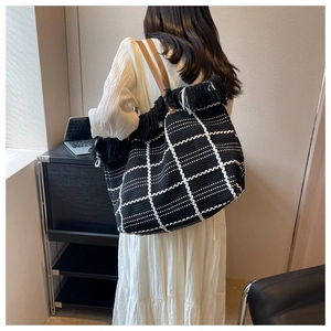 Fashionable woven tote bag with black and white grid pattern and stylish fringe details