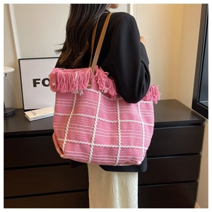 Detailed macro of pink checkered woven tote bag with fringe edge and leather straps