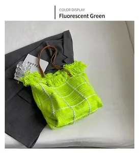 Détail d'un sac cabas tissé vert fluo avec des franges et des anses en cuir marron