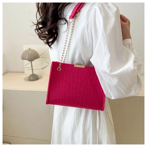Dettaglio borsa in feltro fucsia motivo coccodrillo con elegante catena dorata