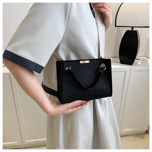 Dettaglio borsa nera texture coccodrillo con catena dorata su una donna