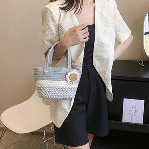 Handmade woven straw shoulder bag with daisy floral detail shown in a lifestyle setting