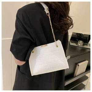Dettaglio borsa bianca con motivo a coccodrillo e catena su giacca nera elegante