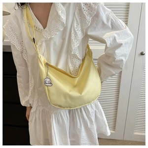 Gros plan d'un sac demi-lune jaune vif en toile avec bandoulière et pendentif chien