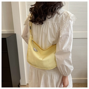 Détail d'un sac à bandoulière demi-lune jaune vif avec un pendentif chiot mignon
