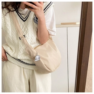 Détail du sac croissant en velours côtelé crème avec bandoulière et breloque nuage