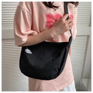 Détail du sac bandoulière en toile noire avec joli pendentif chien de dessin animé