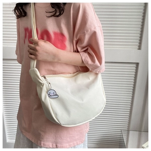 Gros plan du sac hobo en toile blanc cassé avec un charmant pendentif mouton et fermeture