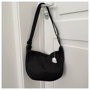 Vue détaillée d'un sac hobo en toile noire avec sangle réglable et bijou de sac