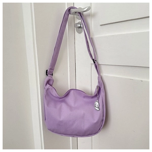 Détail d'un sac demi-lune en velours côtelé violet avec texture douce et breloque