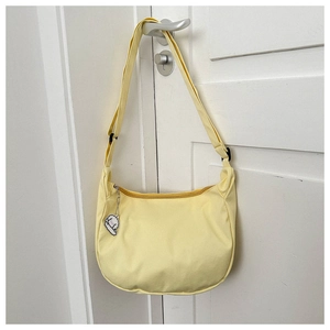Détail du sac bandoulière en toile jaune pâle avec pendentif chien en peluche sur porte