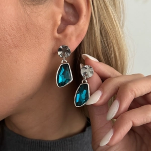 Detail view of geometric drop earrings with blue crystal and hammered silver base