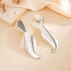 Minimalist silver twist leaf earrings with polished metallic finish on a warm silk background