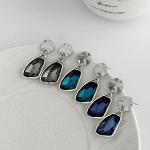 Detailed close-up of faceted crystal drop earrings in grey, teal and navy blue colors