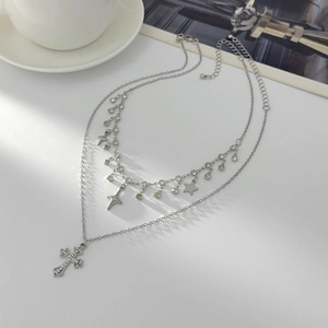 Detail of layered silver necklace with cross and star pendants on a white desk
